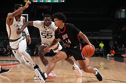 Dec 17, 2022; Coral Gables, Florida, USA; St. Francis Red Flash guard Landon Moore (14) drives the ball around Miami Hurricanes guard Wooga Poplar (55) and forward A.J. Casey (0) during the first half at Watsco Center. Mandatory Credit: Jasen Vinlove-USA TODAY Sports