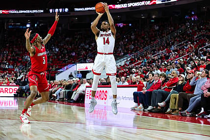 Dec 22, 2022; Raleigh, North Carolina, USA;  North Carolina State Wolfpack guard Casey Morsell (14) shoots a three pointer while guard El Ellis (3) tries to block him during the first half against Louisville Cardinals at PNC Arena. Mandatory Credit: Jaylynn Nash-USA TODAY Sports