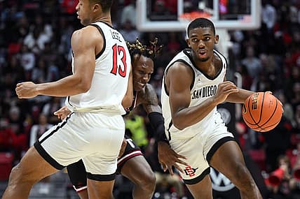 Dec 5, 2022; San Diego, California, USA; Troy Trojans guard Christyon Eugene (center) is screened by San Diego State Aztecs forward Jaedon LeDee (13) as guard Lamont Butler (right) dribbles the ball during the second half at Viejas Arena. Mandatory Credit: Orlando Ramirez-USA TODAY Sports