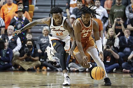 Jan 7, 2023; Stillwater, Oklahoma, USA; Oklahoma State Cowboys forward Kalib Boone (22) and Texas Longhorns guard Marcus Carr (5) reach for a loose ball during the first half at Gallagher-Iba Arena. Mandatory Credit: Alonzo Adams-USA TODAY Sports