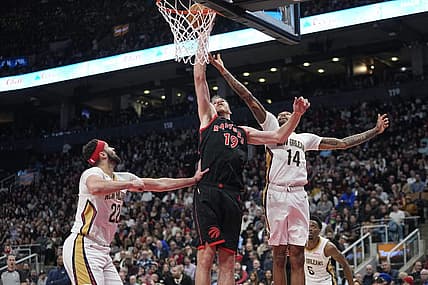 Feb 23, 2023; Toronto, Ontario, CAN; Toronto Raptors center Jakob Poeltl (19) tips in a ball against New Orleans Pelicans forward Brandon Ingram (14) and  forward Larry Nance Jr. (22) during the first half at Scotiabank Arena. Mandatory Credit: John E. Sokolowski-USA TODAY Sports