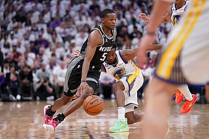 Apr 15, 2023; Sacramento, California, USA; Sacramento Kings guard De'Aaron Fox (5) dribbles past Golden State Warriors forward Andrew Wiggins (22) in the first quarter during game one of the 2023 NBA playoffs at the Golden 1 Center. Mandatory Credit: Cary Edmondson-USA TODAY Sports