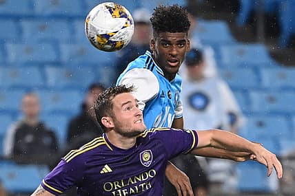Aug 30, 2023; Charlotte, North Carolina, USA; Charlotte FC defender Adilson Malanda (29) heads the ball as Orlando City forward Duncan McGuire (13) defends in the first half at Bank of America Stadium. Mandatory Credit: Bob Donnan-USA TODAY Sports