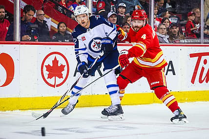 Oct 2, 2023; Calgary, Alberta, CAN; Winnipeg Jets center Mason Appleton (22) and Calgary Flames defenseman Rasmus Andersson (4) battle for the puck during the first period at Scotiabank Saddledome. Mandatory Credit: Sergei Belski-USA TODAY Sports
