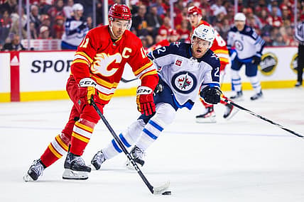 Oct 11, 2023; Calgary, Alberta, CAN; Calgary Flames center Mikael Backlund (11) controls the puck against Winnipeg Jets center Mason Appleton (22) during the first period at Scotiabank Saddledome. Mandatory Credit: Sergei Belski-USA TODAY Sports