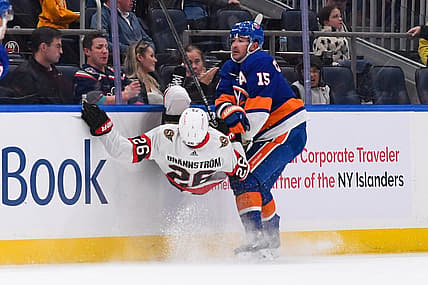 Oct 26, 2023; Elmont, New York, USA; New York Islanders right wing Cal Clutterbuck (15) checks Ottawa Senators defenseman Erik Brannstrom (26) into the boards during the second period at UBS Arena. Mandatory Credit: Dennis Schneidler-USA TODAY Sports