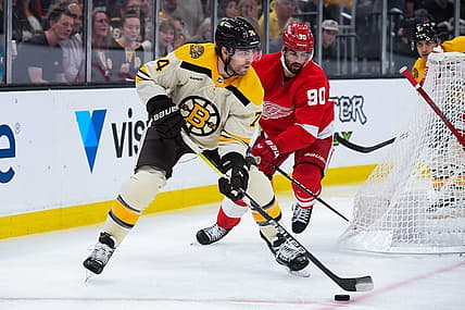 Oct 26, 2023; Boston, Massachusetts, USA;  Boston Bruins left wing Jake DeBrusk (74) controls the puck while Detroit Red Wings center Joe Veleno (90) defends during the first period at TD Garden. Mandatory Credit: Bob DeChiara-USA TODAY Sports