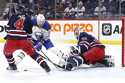 Nov 17, 2023; Winnipeg, Manitoba, CAN; Winnipeg Jets defenseman Neal Pionk (4) and Buffalo Sabres left wing Zemgus Girgensons (28) scramble for a rebound in front of Winnipeg Jets goaltender Connor Hellebuyck (37) in the first period at Canada Life Centre. Mandatory Credit: James Carey Lauder-USA TODAY Sports