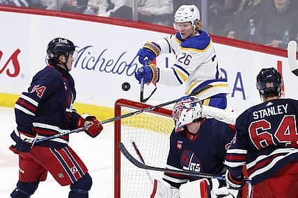Nov 17, 2023; Winnipeg, Manitoba, CAN; Winnipeg Jets defenseman Dylan Samberg (54) and Buffalo Sabres defenseman Rasmus Dahlin (26) bat at the puck behind Winnipeg Jets goaltender Connor Hellebuyck (37) in the third period at Canada Life Centre. Mandatory Credit: James Carey Lauder-USA TODAY Sports