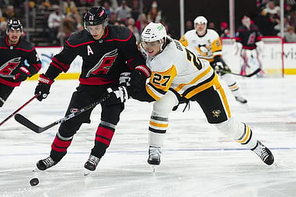 Nov 18, 2023; Raleigh, North Carolina, USA; Carolina Hurricanes center Sebastian Aho (20) tries to control the puck against Pittsburgh Penguins defenseman Ryan Graves (27) during the first period at PNC Arena. Mandatory Credit: James Guillory-USA TODAY Sports