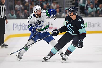 Nov 24, 2023; Seattle, Washington, USA; Vancouver Canucks defenseman Mark Friedman (51) and Seattle Kraken defenseman Brian Dumoulin (8) play the puck during the first period at Climate Pledge Arena. Mandatory Credit: Steven Bisig-USA TODAY Sports