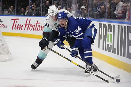 Nov 30, 2023; Toronto, Ontario, CAN; Toronto Maple Leafs forward Auston Matthews (34) battles with Seattle Kracken defenseman Jamie Oleksiak (24) for the puck during the first period at Scotiabank Arena. Mandatory Credit: John E. Sokolowski-USA TODAY Sports