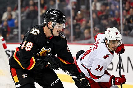 Dec 7, 2023; Calgary, Alberta, CAN; Calgary Flames defenseman Dennis Gilbert (48) competes for the puck against Carolina Hurricanes center Seth Jarvis (24) during the second period of a game at Scotiabank Saddledome. Mandatory Credit: Brett Holmes-USA TODAY Sports