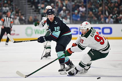Dec 10, 2023; Seattle, Washington, USA; Seattle Kraken left wing Jared McCann (19) passes the puck past Minnesota Wild left wing Kirill Kaprizov (97) during the first period at Climate Pledge Arena. Mandatory Credit: Steven Bisig-USA TODAY Sports