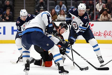 Dec 10, 2023; Anaheim, California, USA;  Anaheim Ducks left wing Brock McGinn (26) fights for the puck against Winnipeg Jets defenseman Brenden Dillon (5) during the second period at Honda Center. Mandatory Credit: Kiyoshi Mio-USA TODAY Sports