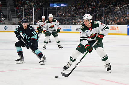 Dec 10, 2023; Seattle, Washington, USA; Minnesota Wild defenseman Brock Faber (7) plays the puck while defended by Seattle Kraken left wing Jared McCann (19) during the third period at Climate Pledge Arena. Mandatory Credit: Steven Bisig-USA TODAY Sports