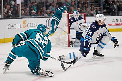 Dec 12, 2023; San Jose, California, USA; San Jose Sharks right wing Kevin Labanc (62) shoots the puck against Winnipeg Jets defenseman Dylan Samberg (54) and goaltender Laurent Brossoit (39) during the second period at SAP Center at San Jose. Mandatory Credit: Robert Edwards-USA TODAY Sports