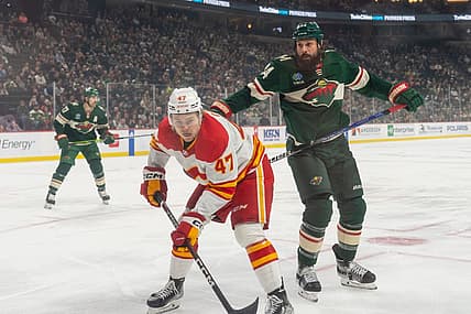 Dec 14, 2023; Saint Paul, Minnesota, USA; Calgary Flames center Connor Zary (47) is challenged by Minnesota Wild defenseman Zach Bogosian (24) in the first period at Xcel Energy Center. Mandatory Credit: Matt Blewett-USA TODAY Sports