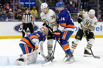 Dec 15, 2023; Elmont, New York, USA; Boston Bruins left wing Jake DeBrusk (74) and left wing Brad Marchand (63) fight for the puck against New York Islanders goaltender Ilya Sorokin (30) and center Bo Horvat (14) during the first period at UBS Arena. Mandatory Credit: Brad Penner-USA TODAY Sports