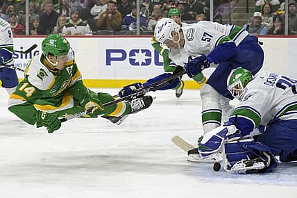 Dec 16, 2023; Saint Paul, Minnesota, USA;  Vancouver Canucks defenseman Tyler Myers (57) sends Minnesota Wild forward Joel Eriksson Ek (14) flying as goalie Casey DeSmith (29) covers the puck during the first period at Xcel Energy Center. Mandatory Credit: Nick Wosika-USA TODAY Sports