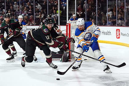 Dec 16, 2023; Tempe, Arizona, USA; Arizona Coyotes left wing Zach Sanford (12) checks Buffalo Sabres defenseman Connor Clifton (75) during the first period at Mullett Arena. Mandatory Credit: Joe Camporeale-USA TODAY Sports