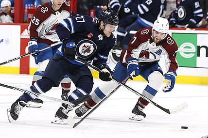 Dec 16, 2023; Winnipeg, Manitoba, CAN; Winnipeg Jets left wing Nikolaj Ehlers (27) is checked by Colorado Avalanche defenseman Devon Toews (7) in the second period at Canada Life Centre. Mandatory Credit: James Carey Lauder-USA TODAY Sports
