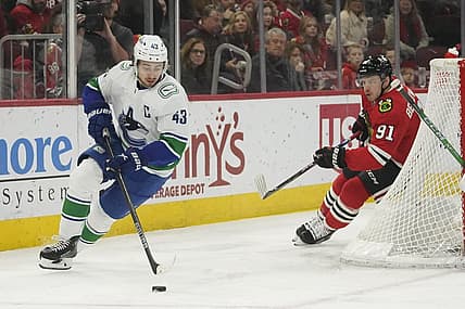 Dec 17, 2023; Chicago, Illinois, USA;   Vancouver Canucks defenseman Quinn Hughes (43) carries the puck chased by Chicago Blackhawks Anthony Beauvillier (91) during the first period at United Center. Mandatory Credit: David Banks-USA TODAY Sports