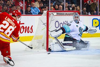 Dec 27, 2023; Calgary, Alberta, CAN; Seattle Kraken goaltender Chris Driedger (60) makes a save against Calgary Flames center Elias Lindholm (28) during the second period at Scotiabank Saddledome. Mandatory Credit: Sergei Belski-USA TODAY Sports