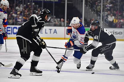 Dec 30, 2023; Los Angeles, California, USA; Edmonton Oilers center Leon Draisaitl (29) moves the puck against Los Angeles Kings center Trevor Lewis (61) and center Anze Kopitar (11) during the first period at Crypto.com Arena. Mandatory Credit: Gary A. Vasquez-USA TODAY Sports