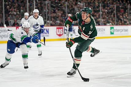 Feb 19, 2024; Saint Paul, Minnesota, USA; Minnesota Wild center Joel Eriksson Ek (14) shoots as Vancouver Canucks right wing Conor Garland (8) defends in the second period at Xcel Energy Center. Mandatory Credit: Matt Blewett-USA TODAY Sports