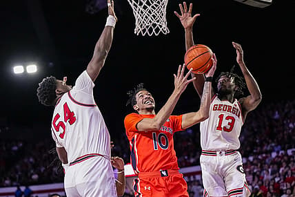 Feb 24, 2024; Athens, Georgia, USA; Auburn Tigers guard Chad Baker-Mazara (10) goes to the basket between Georgia Bulldogs center Russel Tchewa (54) and forward Dylan James (13) at Stegeman Coliseum. Mandatory Credit: Dale Zanine-USA TODAY Sports