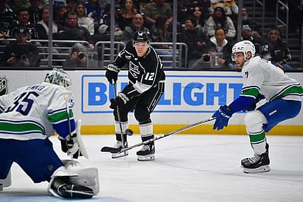 Mar 5, 2024; Los Angeles, California, USA; Los Angeles Kings left wing Trevor Moore (12) shoots on goal against Vancouver Canucks defenseman Carson Soucy (7) and goaltender Thatcher Demko (35) during the second period at Crypto.com Arena. Mandatory Credit: Gary A. Vasquez-USA TODAY Sports