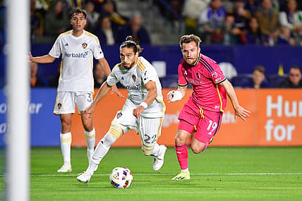Mar 16, 2024; Carson, California, USA; LA Galaxy defender Martin Caceres (22) and St. Louis CITY SC midfielder Indiana Vassilev (19) chase down the ball during the first half at Dignity Health Sports Park. Mandatory Credit: Gary A. Vasquez-USA TODAY Sports