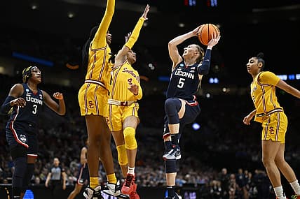 Apr 1, 2024; Portland, OR, USA; UConn Huskies guard Paige Bueckers (5) drives to the basket during the first half against USC Trojans guard Kayla Williams (4) and center Clarice Akunwafo (34)in the finals of the Portland Regional of the NCAA Tournament at the Moda Center. Mandatory Credit: Troy Wayrynen-USA TODAY Sports