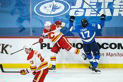 Feb 1, 2021; Winnipeg, Manitoba, CAN;  Calgary Flames defenseman Nikita Nesterov (89) and Winnipeg Jets forward Adam Lowry (17) react to a collision during the first period at Bell MTS Place. Mandatory Credit: Terrence Lee-USA TODAY Sports