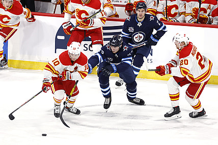 Feb 2, 2021; Winnipeg, Manitoba, CAN.;  Winnipeg Jets Left Wing Kristian Vesalainen (93)  drives for the puck between Calgary Flames center Derek Ryan (10) and Calgary Flames center Joakim Nordstrom (20) in the first period at Bell MTS Place. Mandatory Credit: James Carey Lauder-USA TODAY Sports