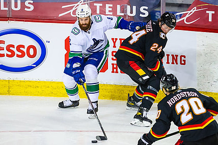 Feb 17, 2021; Calgary, Alberta, CAN; Vancouver Canucks defenseman Jordie Benn (8) and Calgary Flames right wing Brett Ritchie (24) battle for the puck during the first period at Scotiabank Saddledome. Mandatory Credit: Sergei Belski-USA TODAY Sports