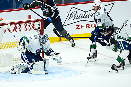 Mar 2, 2021; Winnipeg, Manitoba, CAN;  Vancouver Canucks goalie Braden Holtby (49) smothers the puck in front of Winnipeg Jets forward Matthieu Perreault (85) during the first period at Bell MTS Place. Mandatory Credit: Terrence Lee-USA TODAY Sports