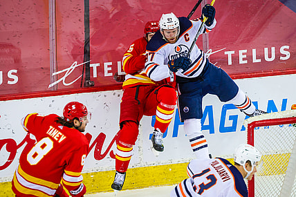 Mar 15, 2021; Calgary, Alberta, CAN; Edmonton Oilers center Connor McDavid (97) checks into the boards Calgary Flames defenseman Noah Hanifin (55) during the second period at Scotiabank Saddledome. Mandatory Credit: Sergei Belski-USA TODAY Sports