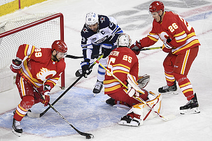 Mar 29, 2021; Calgary, Alberta, CAN; Winnipeg Jets forward Blake Wheeler (26) battles for the puck with Calgary Flames defenseman Nikita Nesterov (89) goalie Jacob Markstrom (25) and defenseman Michael Stone (26) during the second period at Scotiabank Saddledome. Mandatory Credit: Candice Ward-USA TODAY Sports