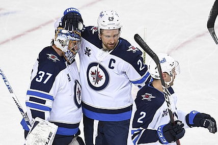 Mar 29, 2021; Calgary, Alberta, CAN; Winnipeg Jets goalie Connor Hellebuyck (37) celebrates with forward Blake Wheeler (26) after a victory over the Calgary Flames at Scotiabank Saddledome. Mandatory Credit: Candice Ward-USA TODAY Sports