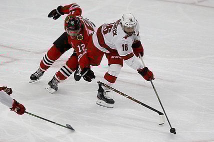 Mar 30, 2021; Chicago, Illinois, USA; Chicago Blackhawks Alex DeBrincat (12) battles for the puck with Carolina Hurricanes Vincent Trocheck (16) during the third period at United Center. Mandatory Credit: Eileen T. Meslar-USA TODAY Sports