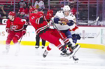 Apr 6, 2021; Raleigh, North Carolina, USA;  Florida Panthers center Eetu Luostarinen (27) checks Carolina Hurricanes left wing Jordan Martinook (48) during the first period at PNC Arena. Mandatory Credit: James Guillory-USA TODAY Sports