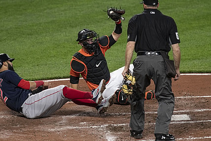 Apr 10, 2021; Baltimore, Maryland, USA; Baltimore Orioles catcher Chance Sisco (15) holds the ball up for home plate umpire Marvin Hudson (51) after tagging out Boston Red Sox third baseman Marwin Gonzalez (12) at the plate  at Oriole Park at Camden Yards. Mandatory Credit: Tommy Gilligan-USA TODAY Sports