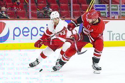 Apr 12, 2021; Raleigh, North Carolina, USA; Carolina Hurricanes defenseman Jaccob Slavin (74) and Detroit Red Wings left wing Darren Helm (43) battle over the puck during the first period at PNC Arena. Mandatory Credit: James Guillory-USA TODAY Sports