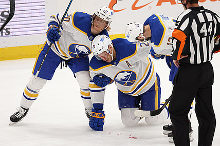 Apr 15, 2021; Washington, District of Columbia, USA; Buffalo Sabres right wing Kyle Okposo (21) is helped to his feet by Sabres center Cody Eakin (20) and Sabres left wing Tobias Rieder (13) after being struck in the face by the puck against the Washington Capitals in the first period at Capital One Arena. Mandatory Credit: Geoff Burke-USA TODAY Sports