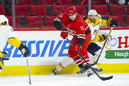 Apr 17, 2021; Raleigh, North Carolina, USA;  Carolina Hurricanes left wing Warren Foegele (13) battles for the puck against Nashville Predators defenseman Ryan Ellis (4) during the first period at PNC Arena. Mandatory Credit: James Guillory-USA TODAY Sports