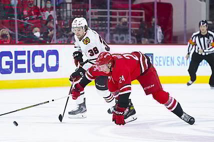 May 4, 2021; Raleigh, North Carolina, USA;  Carolina Hurricanes defenseman Jake Bean (24) and Chicago Blackhawks left wing Brandon Hagel (38 battle for the puck during the first period at PNC Arena. Mandatory Credit: James Guillory-USA TODAY Sports
