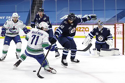 May 11, 2021; Winnipeg, Manitoba, CAN; Vancouver Canucks center Zack MacEwen (71) and Winnipeg Jets defenseman Jordie Benn (40) battle for the puck during the first period at Bell MTS Place. Mandatory Credit: James Carey Lauder-USA TODAY Sports