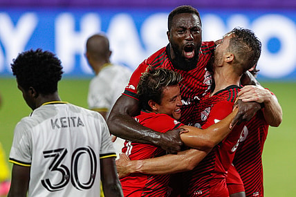 May 12, 2021; Orlando, Florida, CAN; Toronto FC forward Jozy Altidore (top) celebrates with forward Tsubasa Endoh (31) and defender Omar Gonzalez (right) after scoring a goal during the second half against Columbus Crew FC at Orlando City Stadium. Mandatory Credit: Nathan Ray Seebeck-USA TODAY Sports